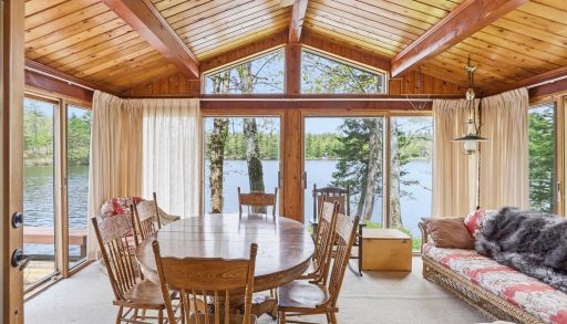 A wood dining table in a sunroom facing the lake