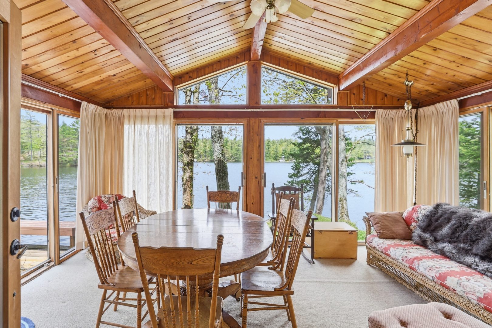 A wood dining table in a sunroom facing the lake
