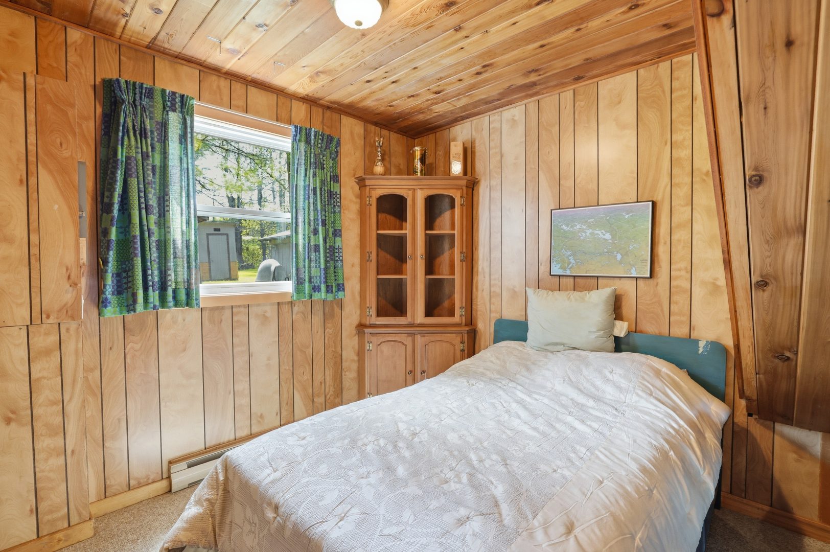 A white bed in a wood-panelled bedroom
