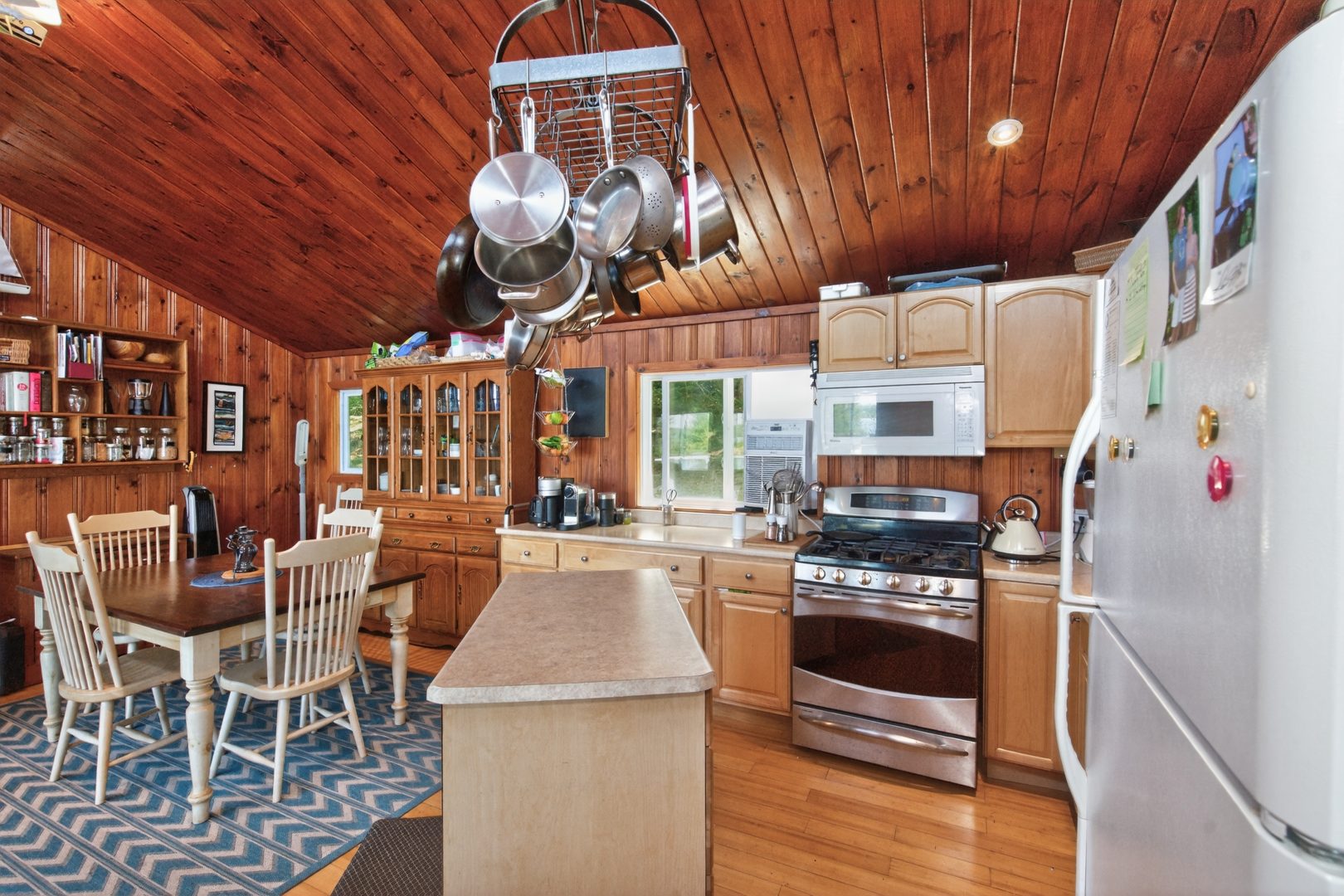 An open-concept kitchen next to a small wood dining area in a wood-paneled room