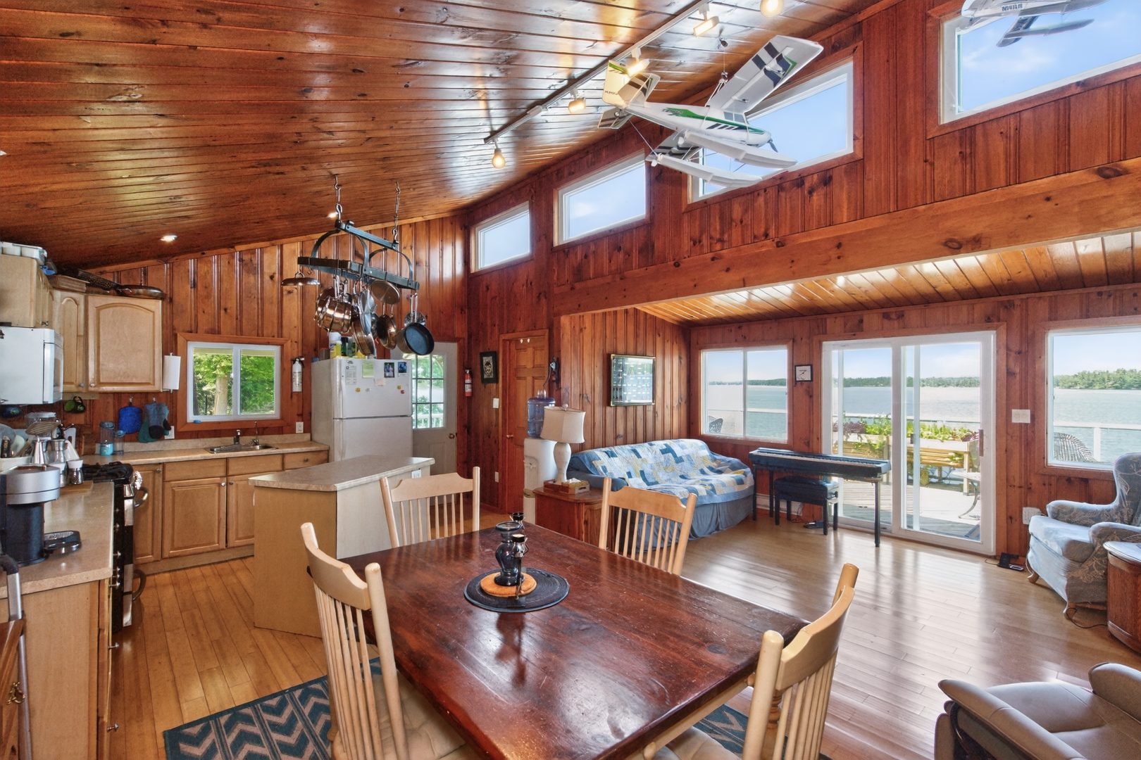 A wood paneled living area with a wood dining table and bright windows