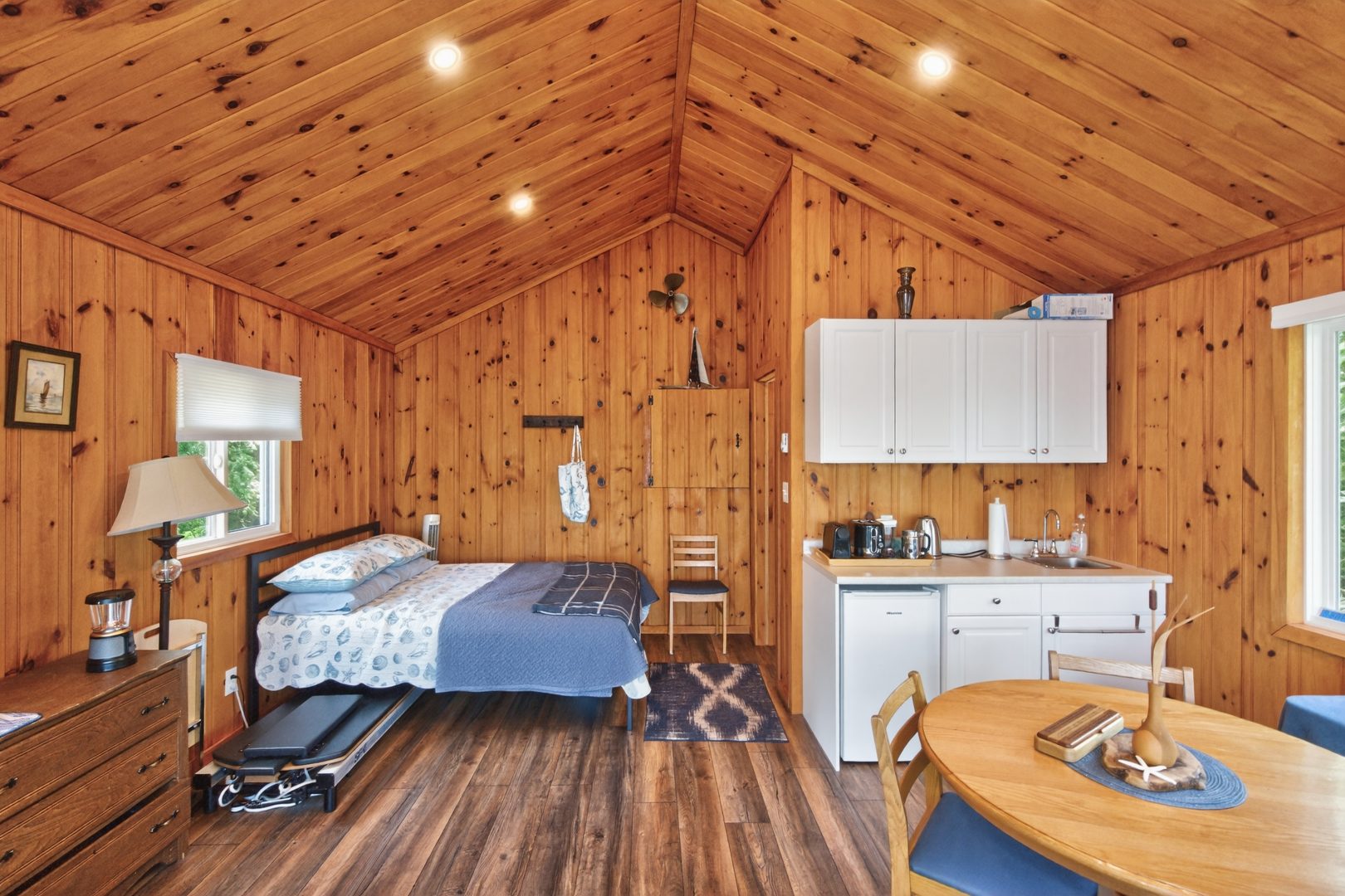 A wood-paneled room with a bed and small kitchenette