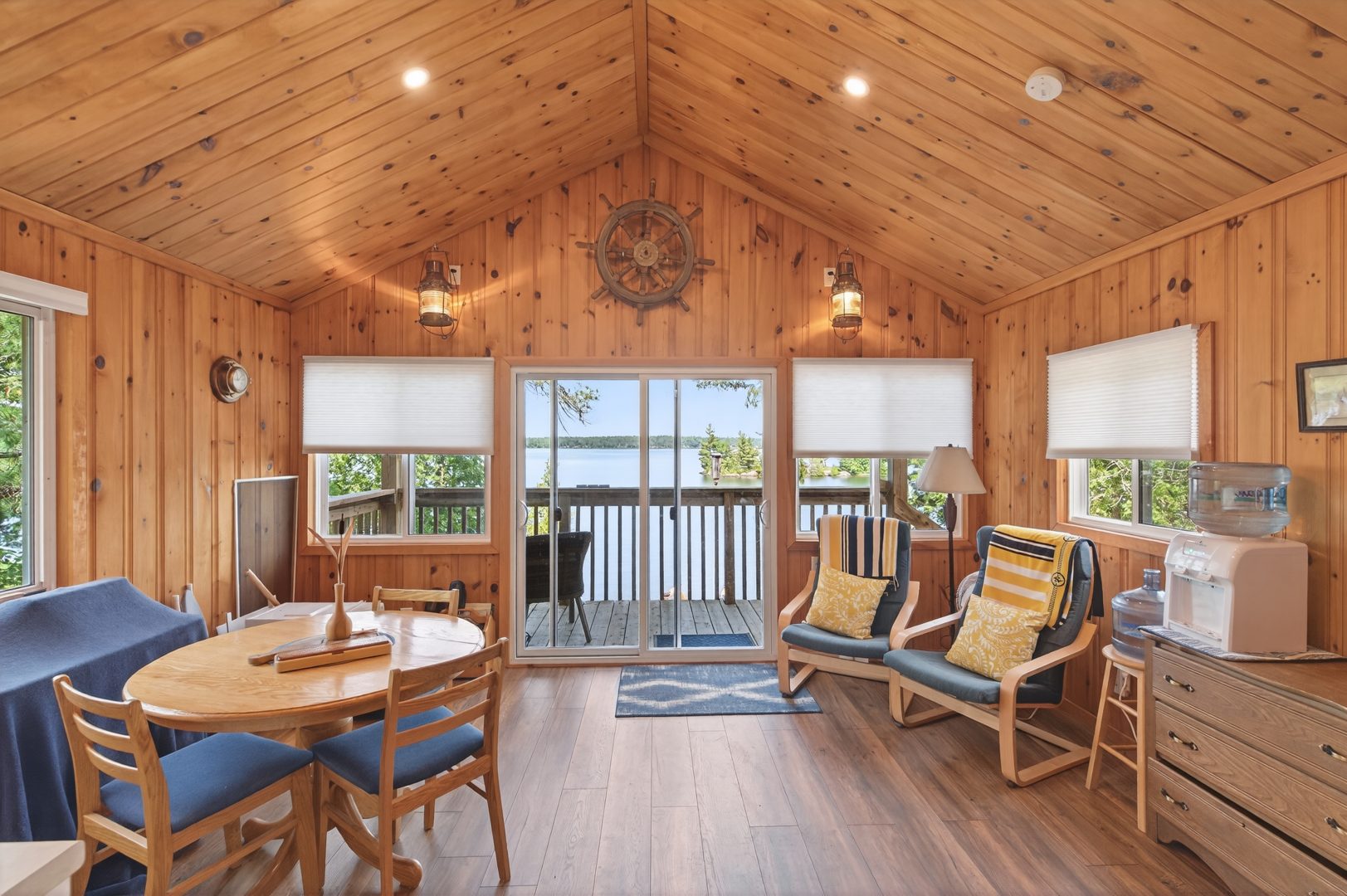 A wood interior with a small table and sitting area that looks out onto the lake