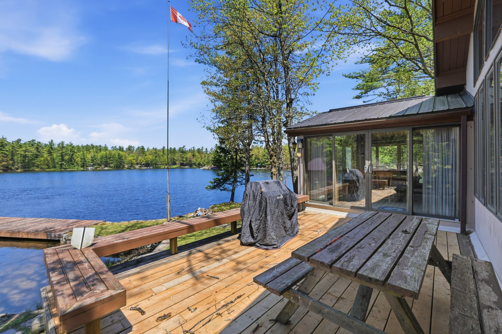 A wood deck with a picnic table looks out onto the lake