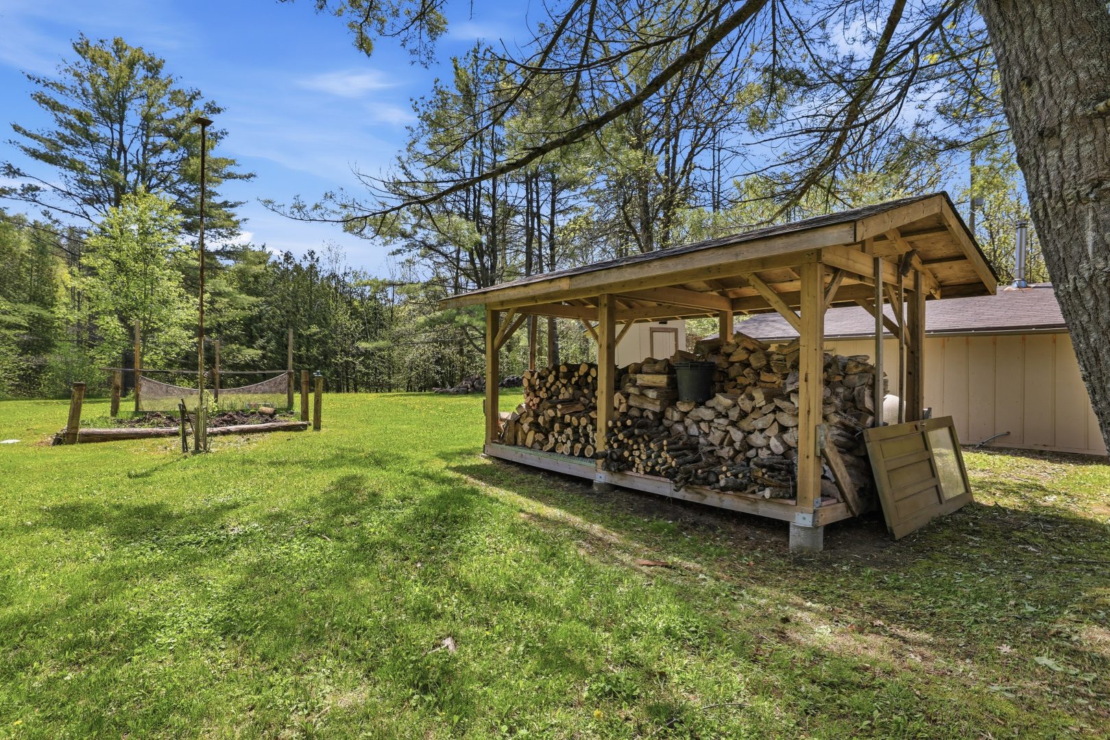 A grassy lawn with a covered stack of logs