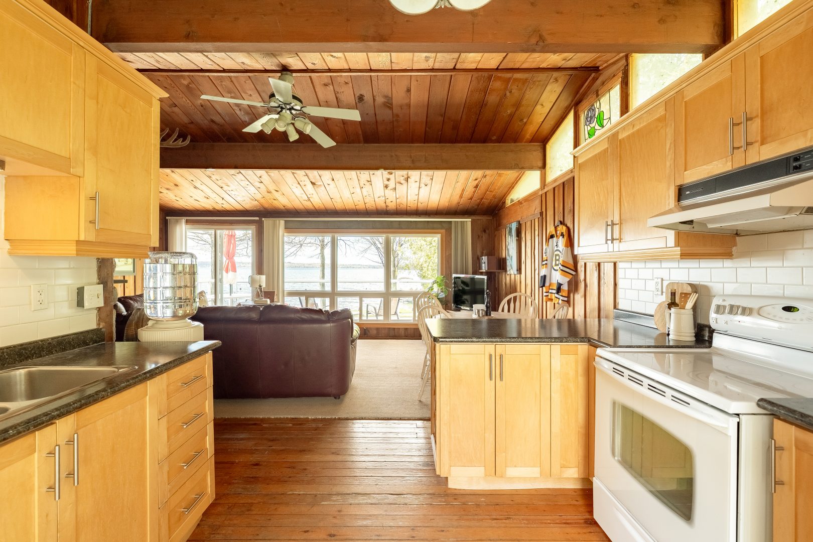 A wood-paneled kitchen with grey countertops faces a bright living area