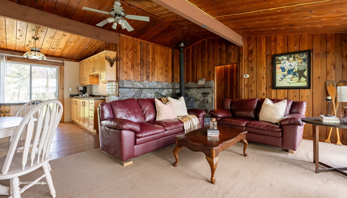 Leather couches face a wood coffee table in a wood-clad living room