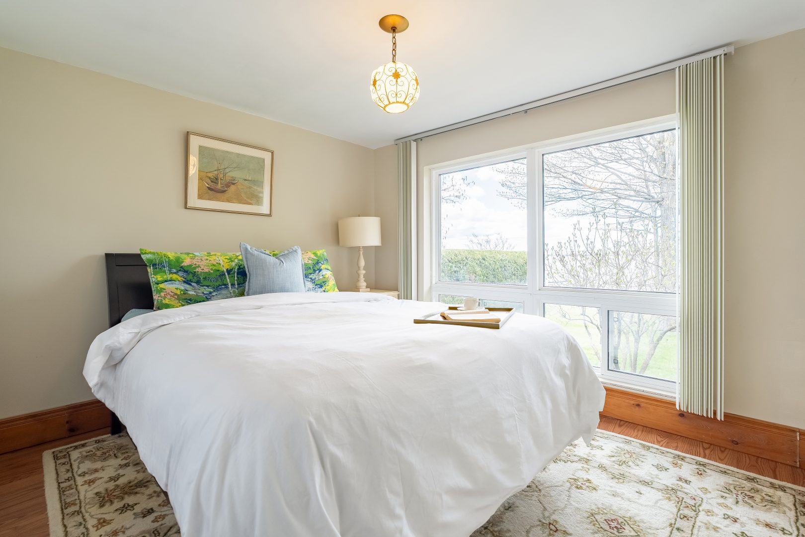 A white bed with green cushions in a bright white bedroom