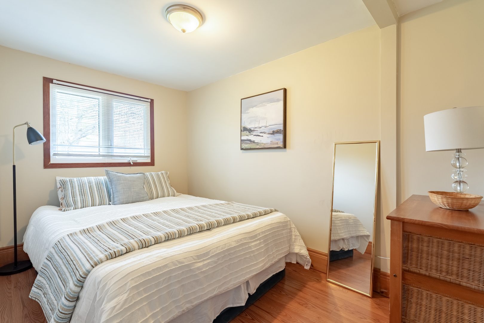 A white bed with a grey throw in a white bedroom