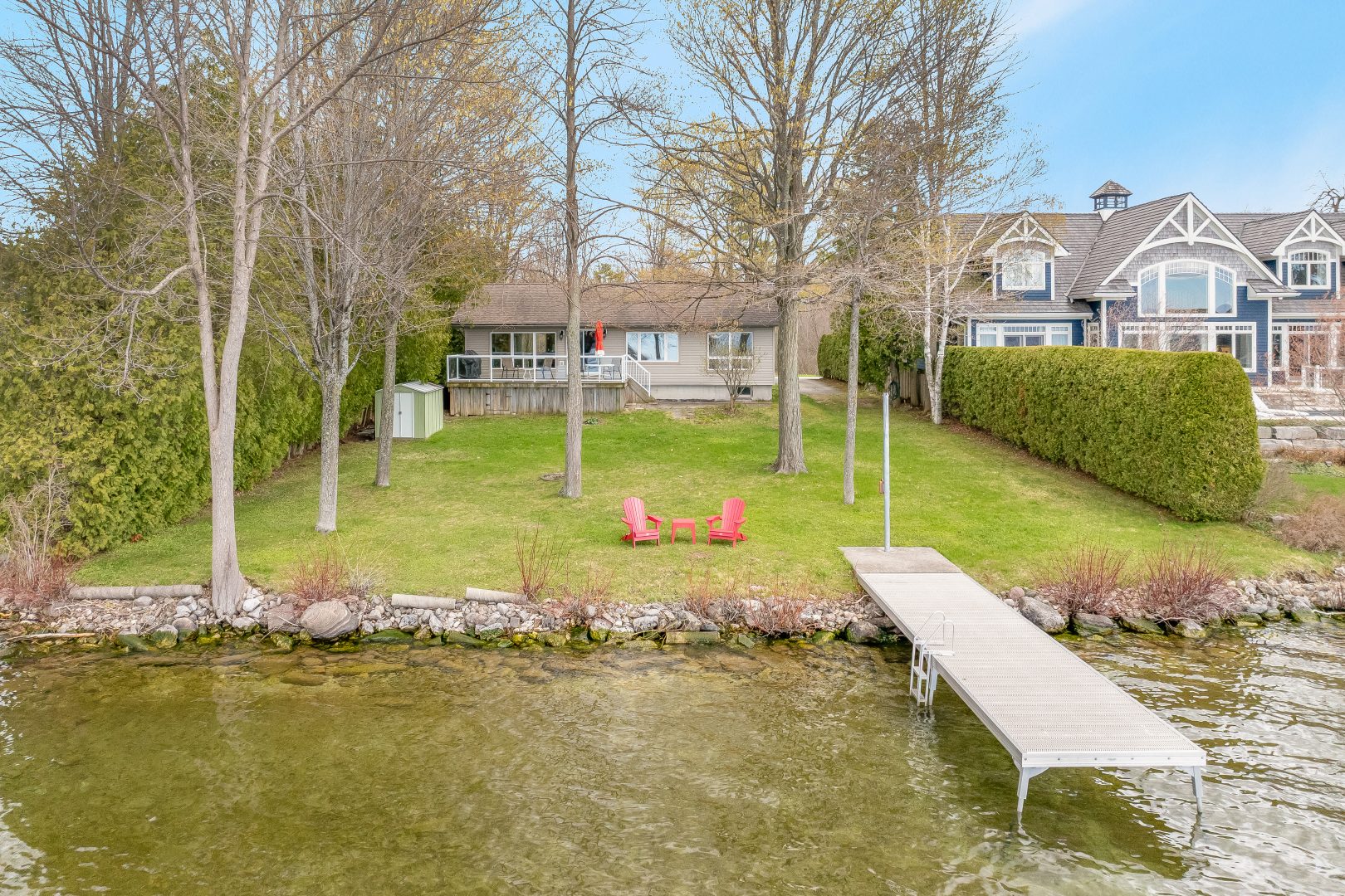 A grassy yard on a waterfront with a dock jutting out into the water