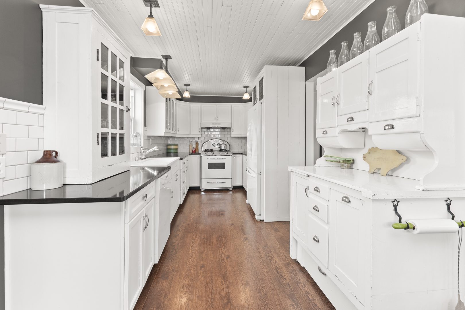 A white kitchen with grey trim and brown wood floors