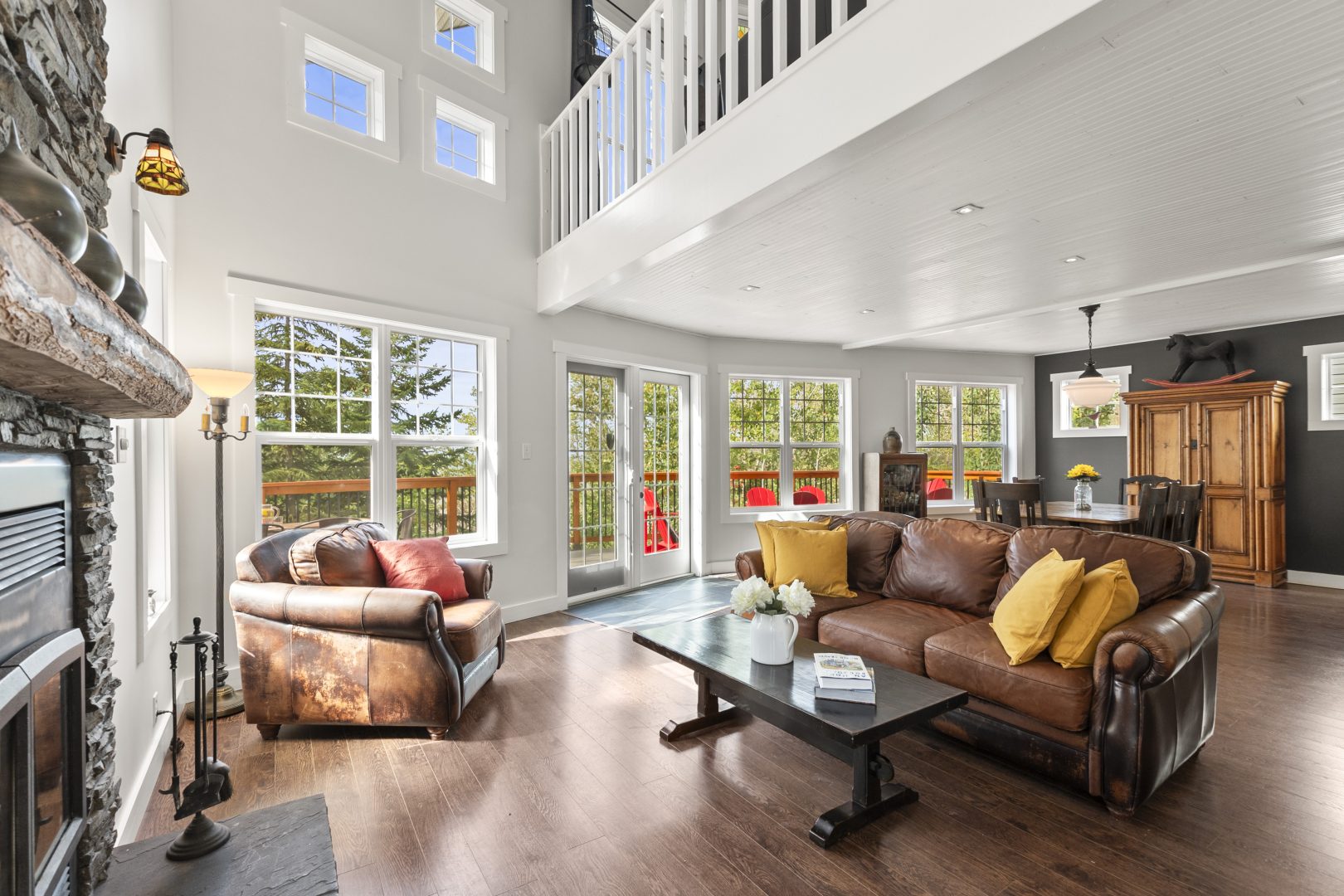 A dark brown leather couch faces a chair in a sunny living area