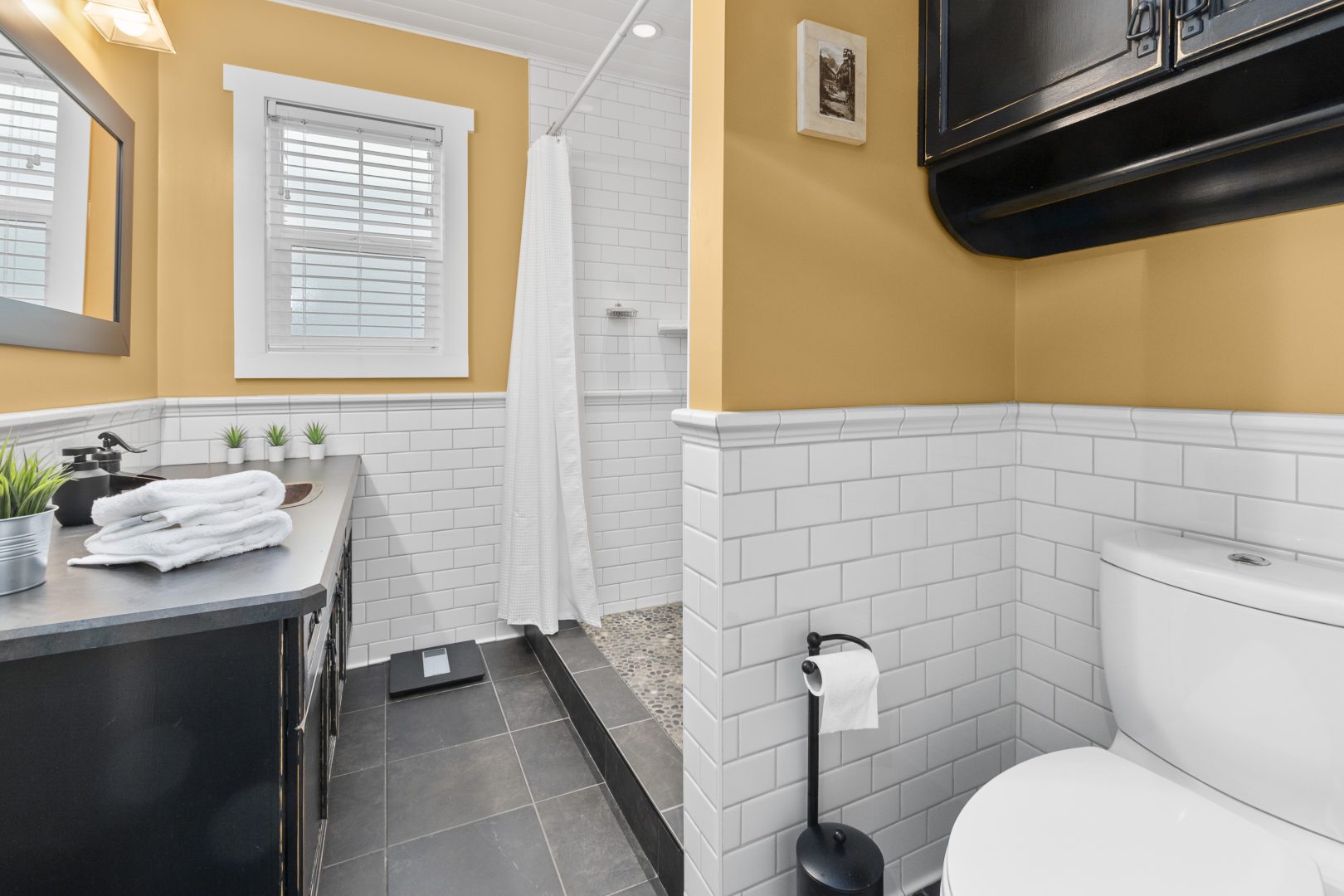 A small bathroom with yellow walls and white tiles