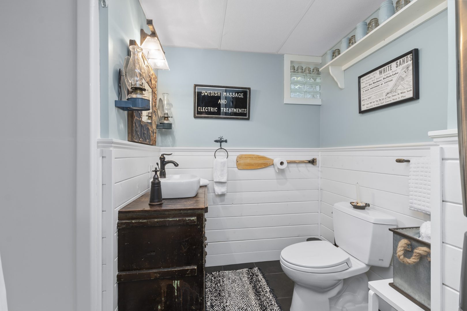 A white and light blue bathroom with a dark wood vanity