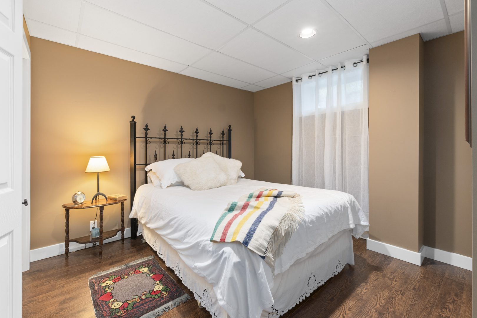 A white bed with a striped Hudson's Bay throw