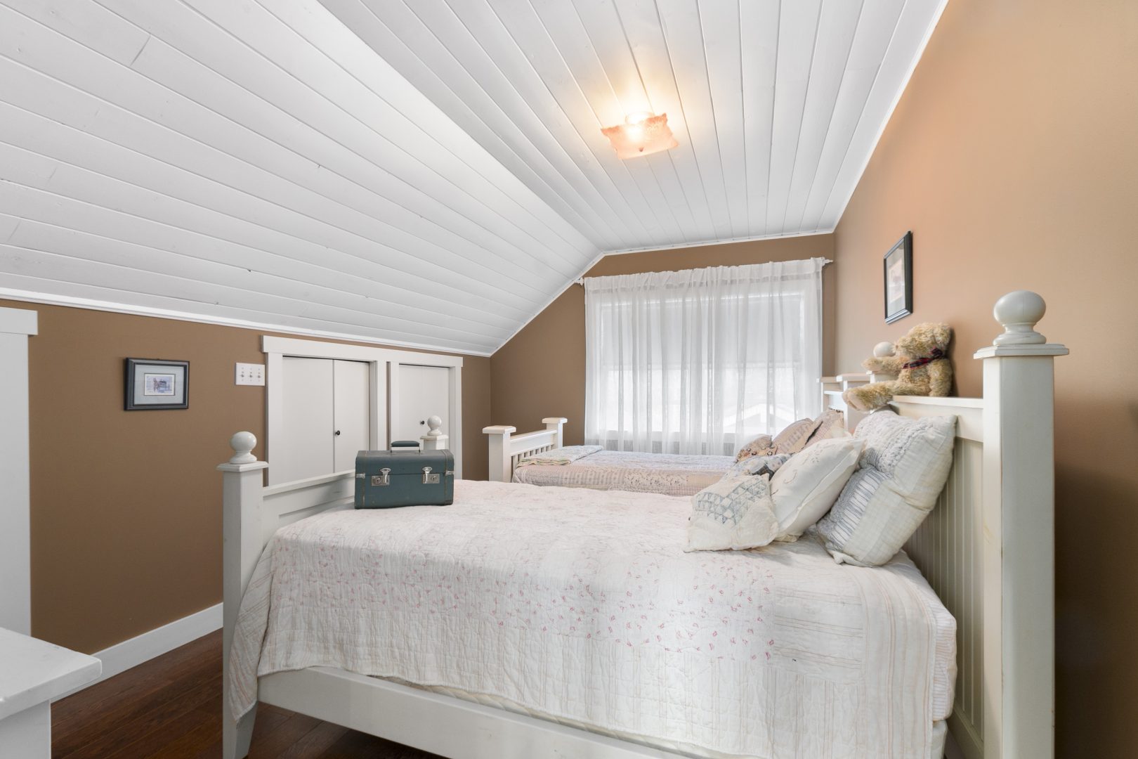 Two white beds facing a white closet in a light brown room