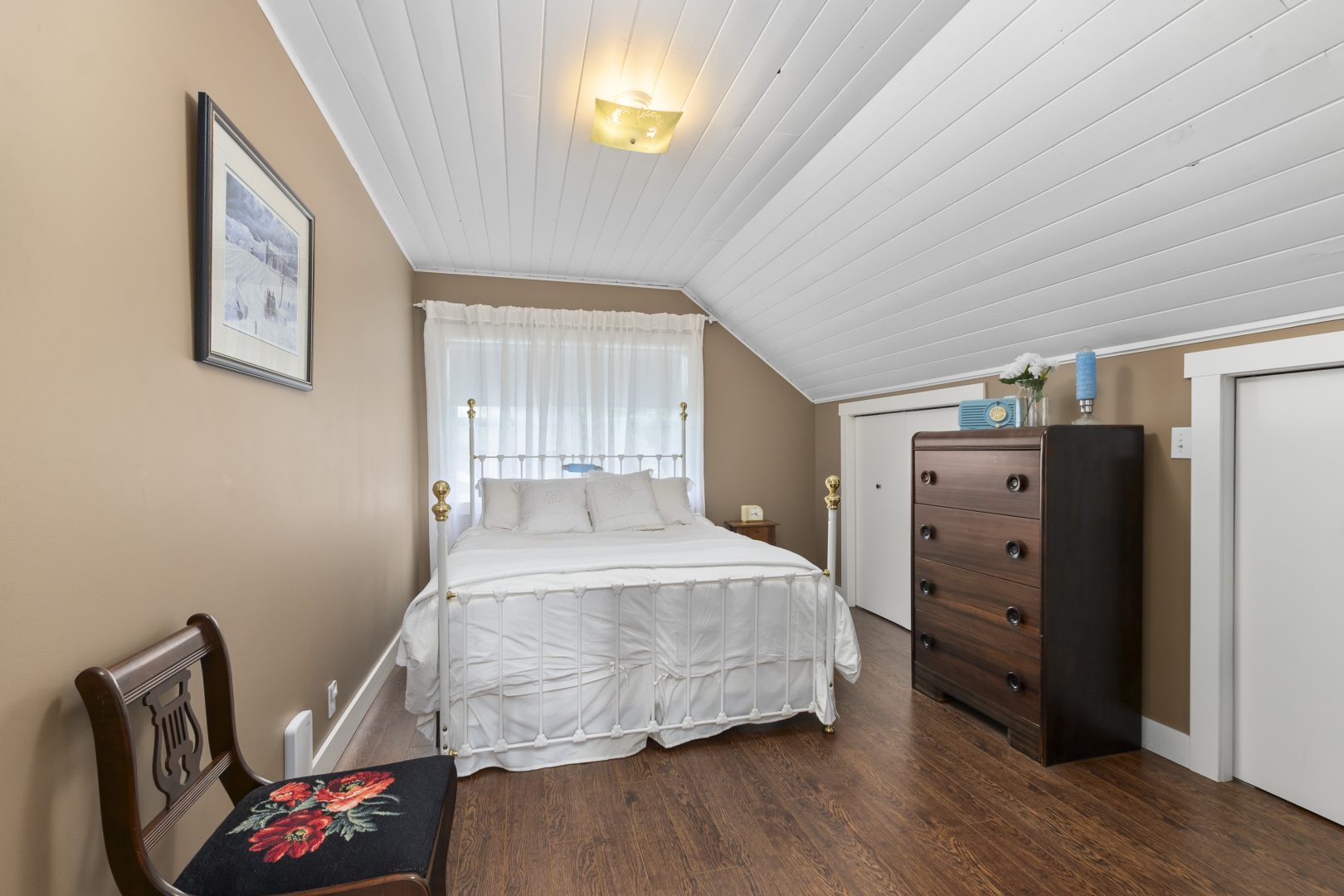 A white bed in a beige bedroom with white paneled ceilings