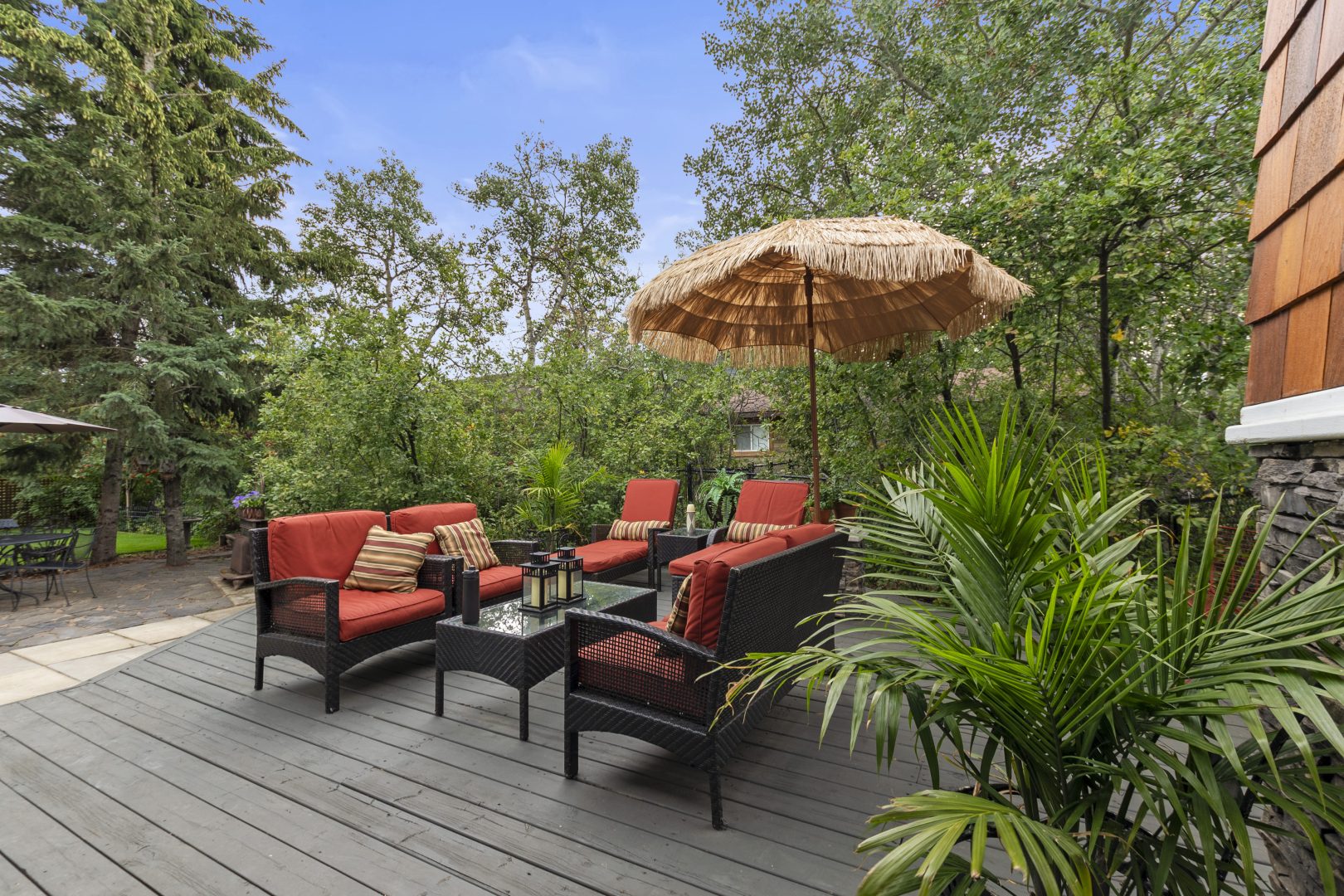 Black patio furniture with red cushions and patterned umbrella