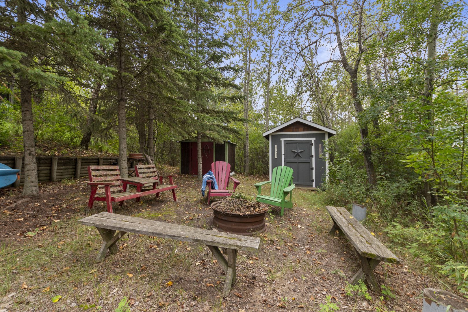 Muskoka chairs and wood benches surround a fire pit
