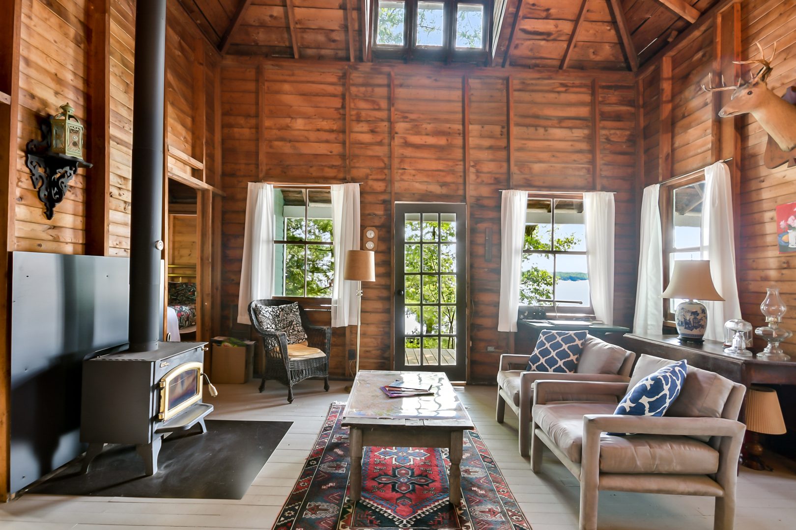 A wood living room with eclectic furniture and a wood stove