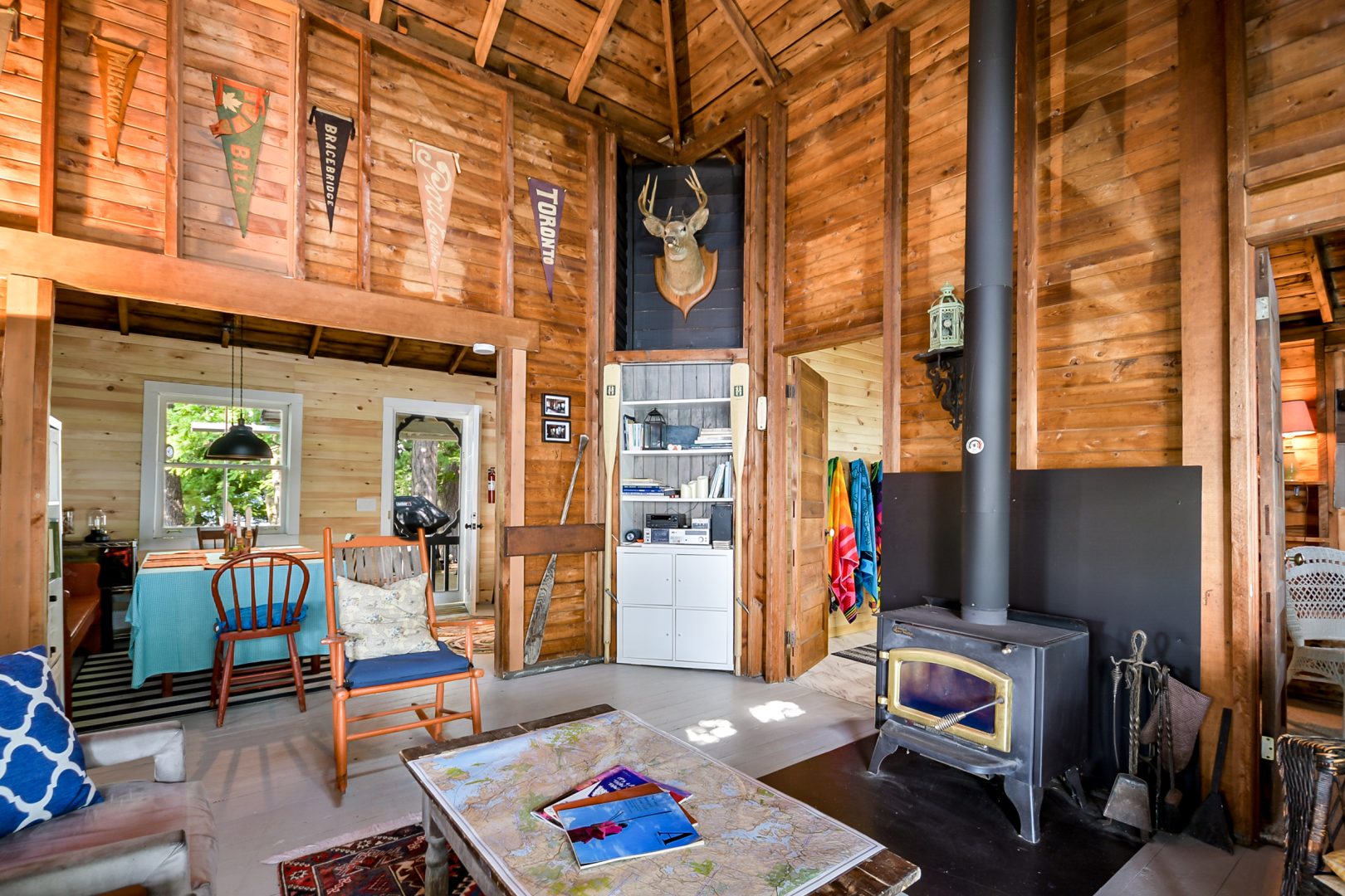 A wood-paneled living room with a wood stove, couches and tall ceilings