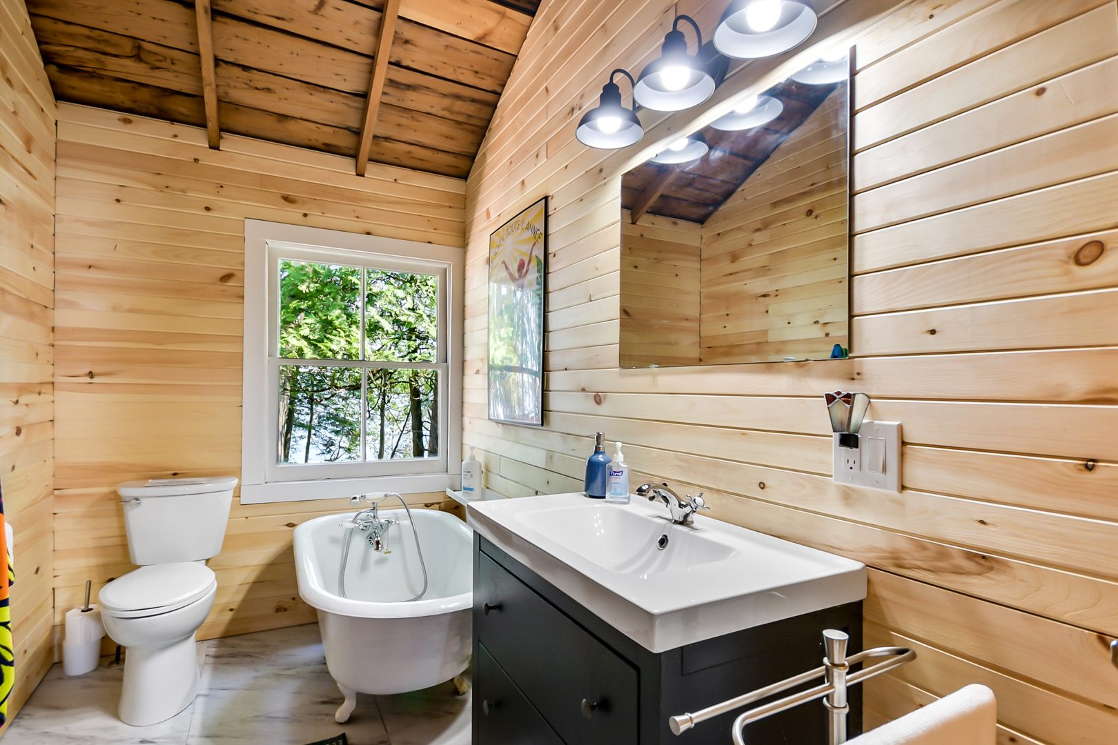 A wood-paneled bathroom with a clawfoot tub and a black vanity