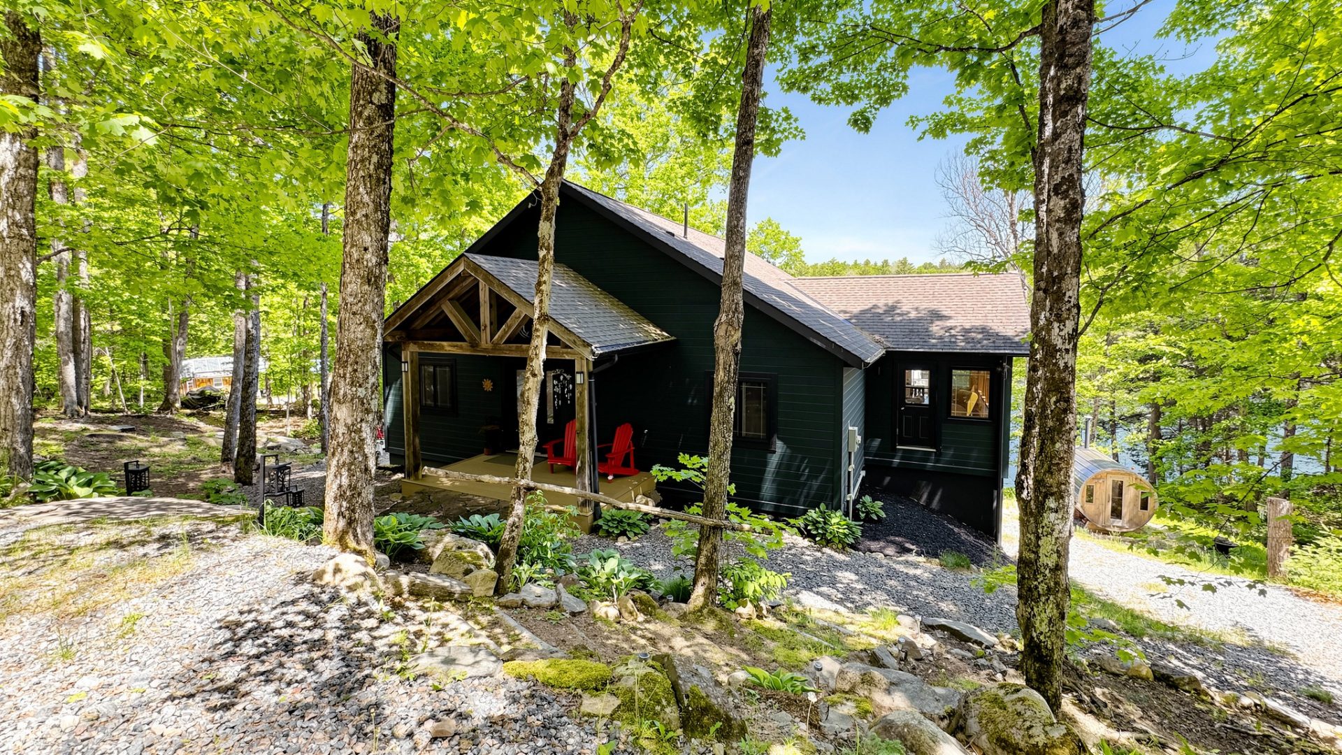 A black A-frame clapboard cottage entrance with a red door