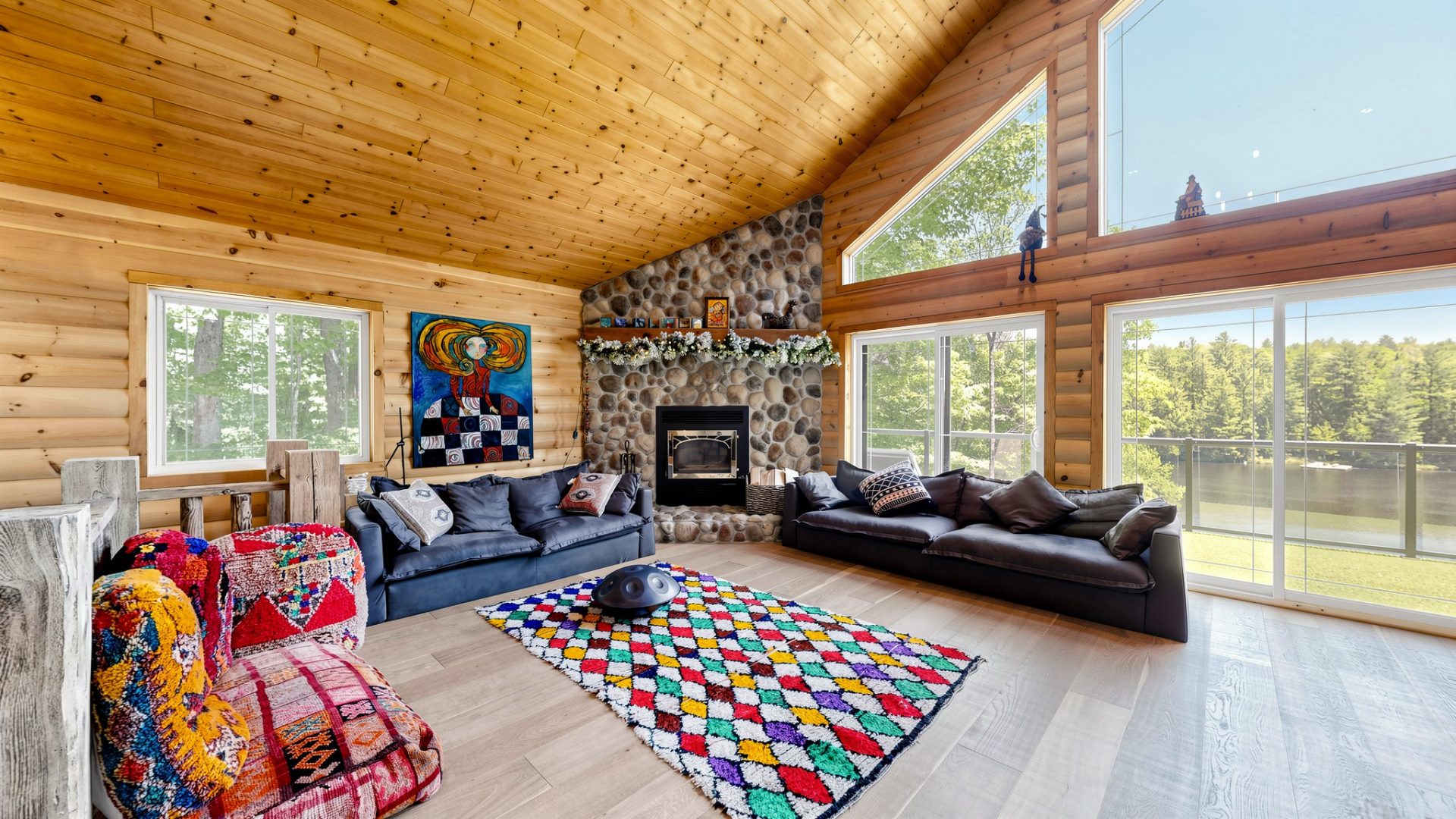 A wood-clad living room with a stone fireplace and two couches
