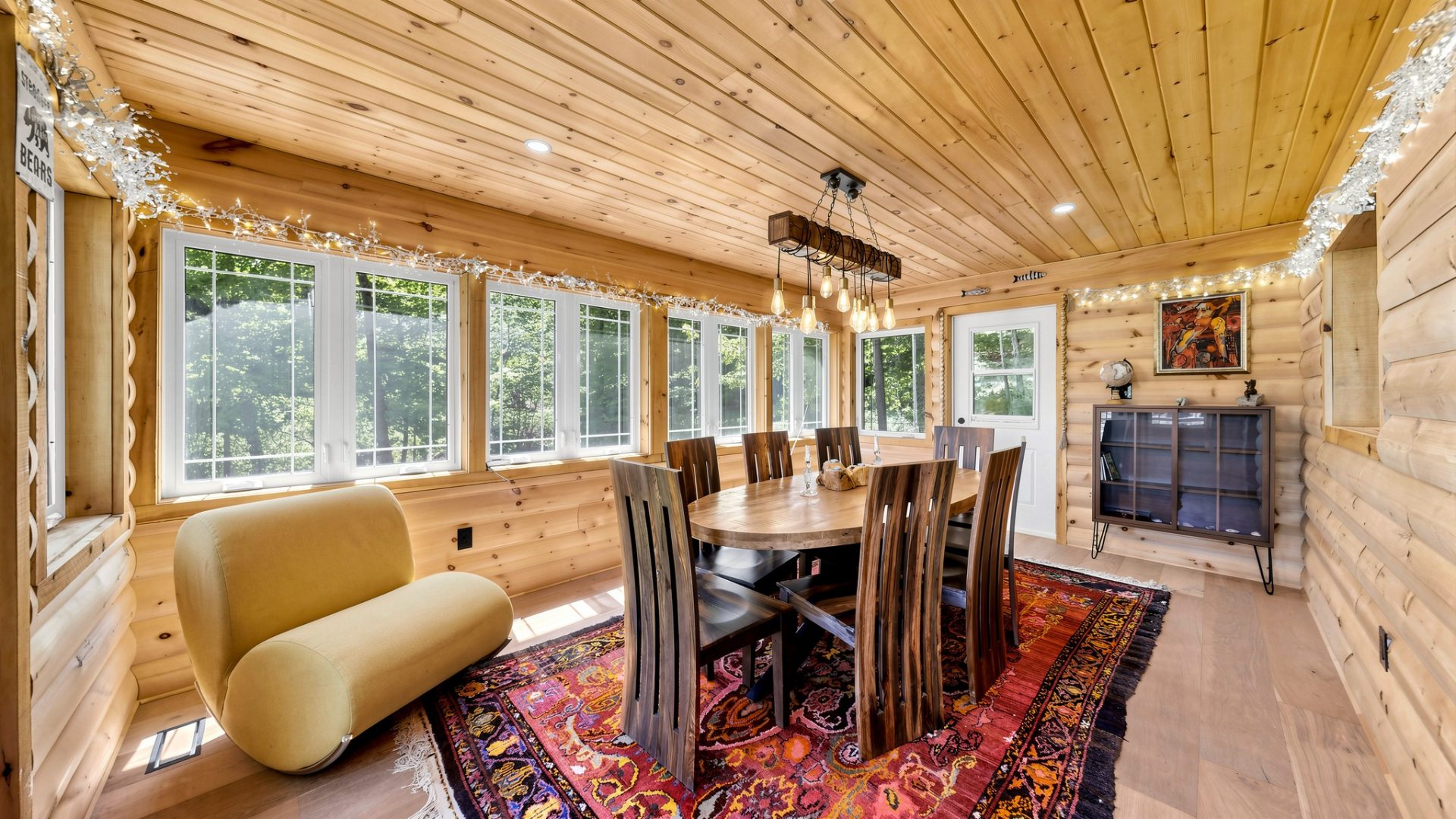 A round wood table with high-back wood chairs in a sunroom