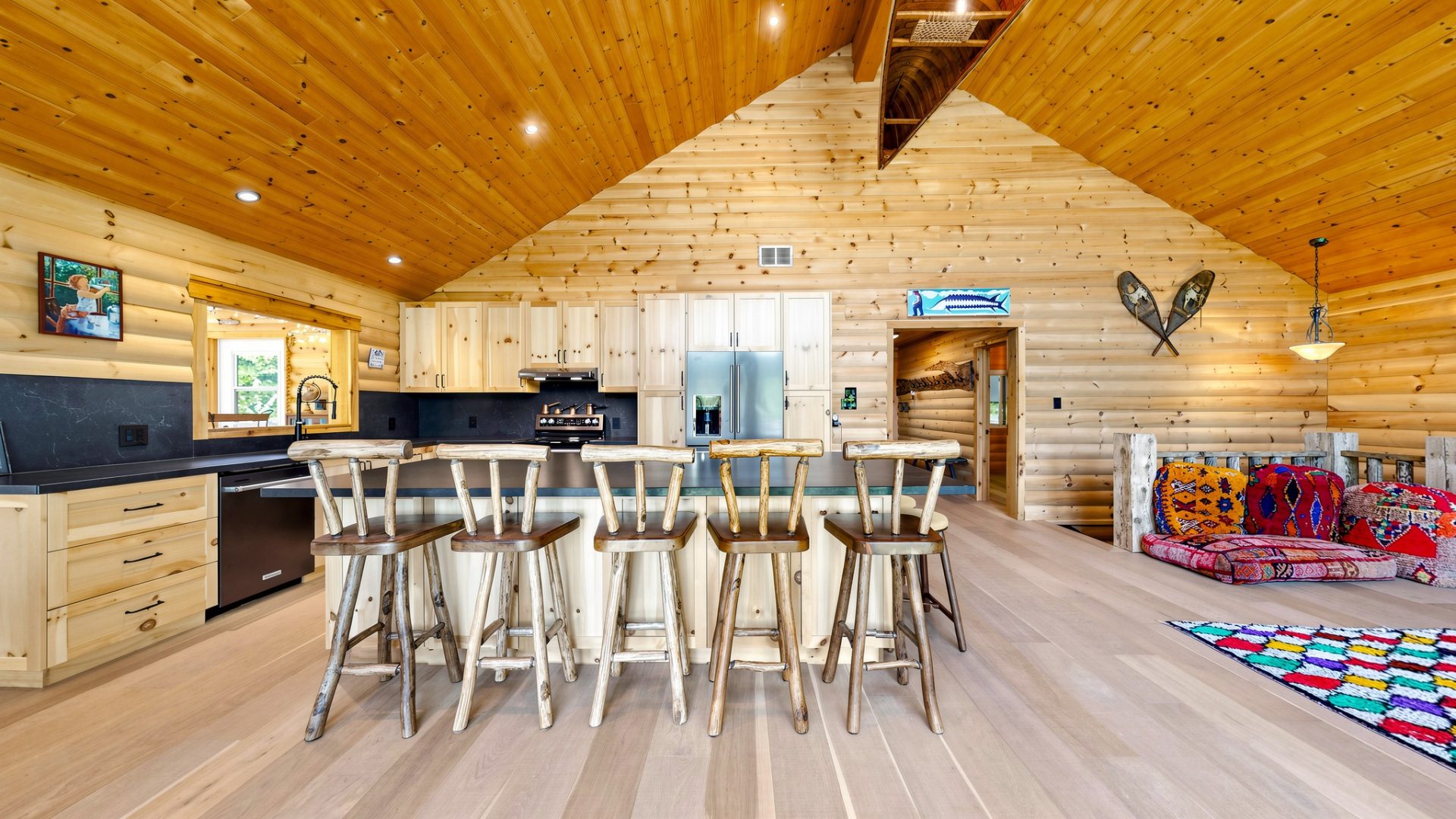 High-top chairs sit at a kitchen island in a wood-clad room