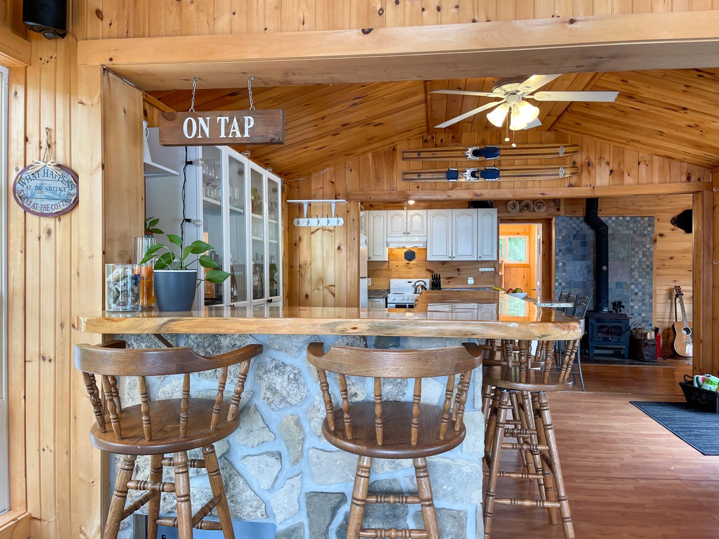 A stone high-top seating area on the edge of a kitchen with wood-paneled walls and ceilings