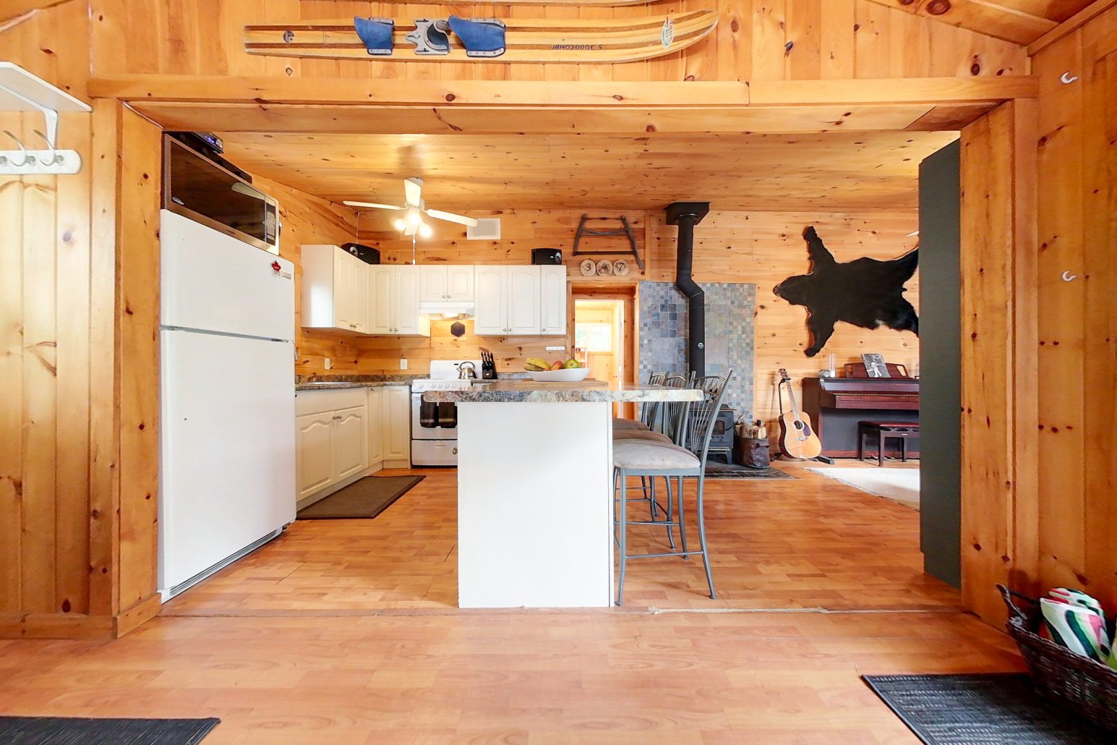 A white open-concept kitchen with a wood paneled ceiling