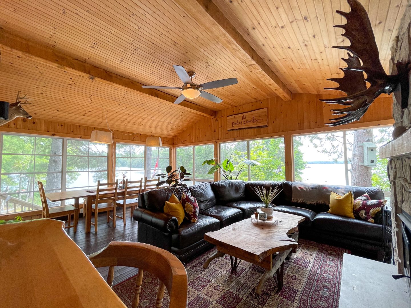 A couch with colourful pillows faces a coffee table in a bright cottage living room