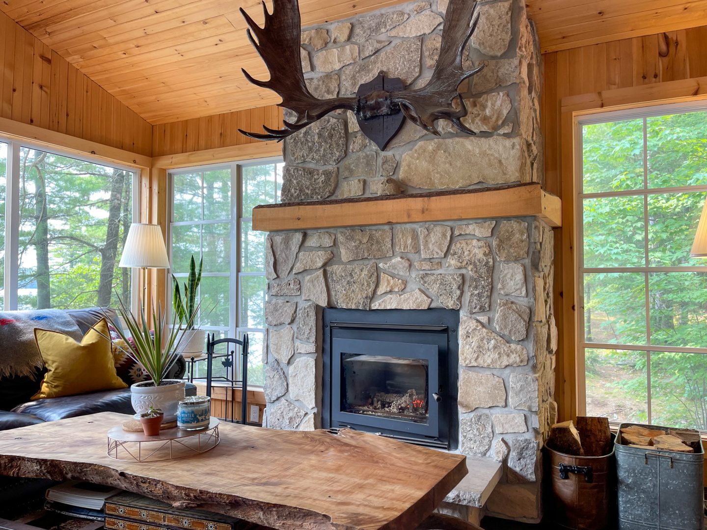 A stone fireplace with moose antlers hanging above