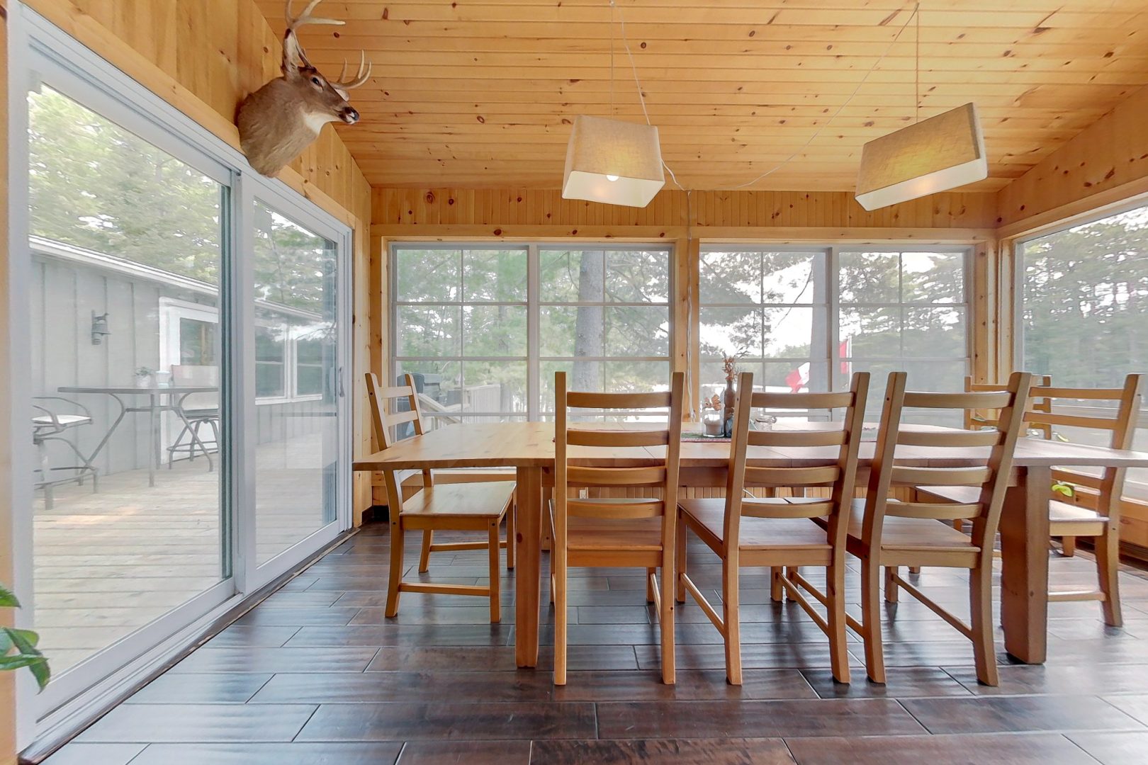 A wood dining table with matching chairs in a screened-in room