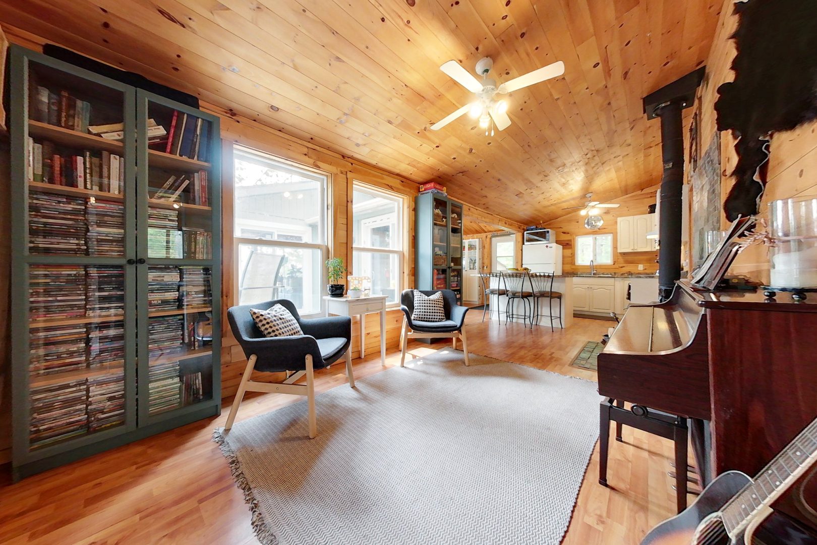 Two blue chairs flanked by glass-paneled game cupboards in a bright cottage room