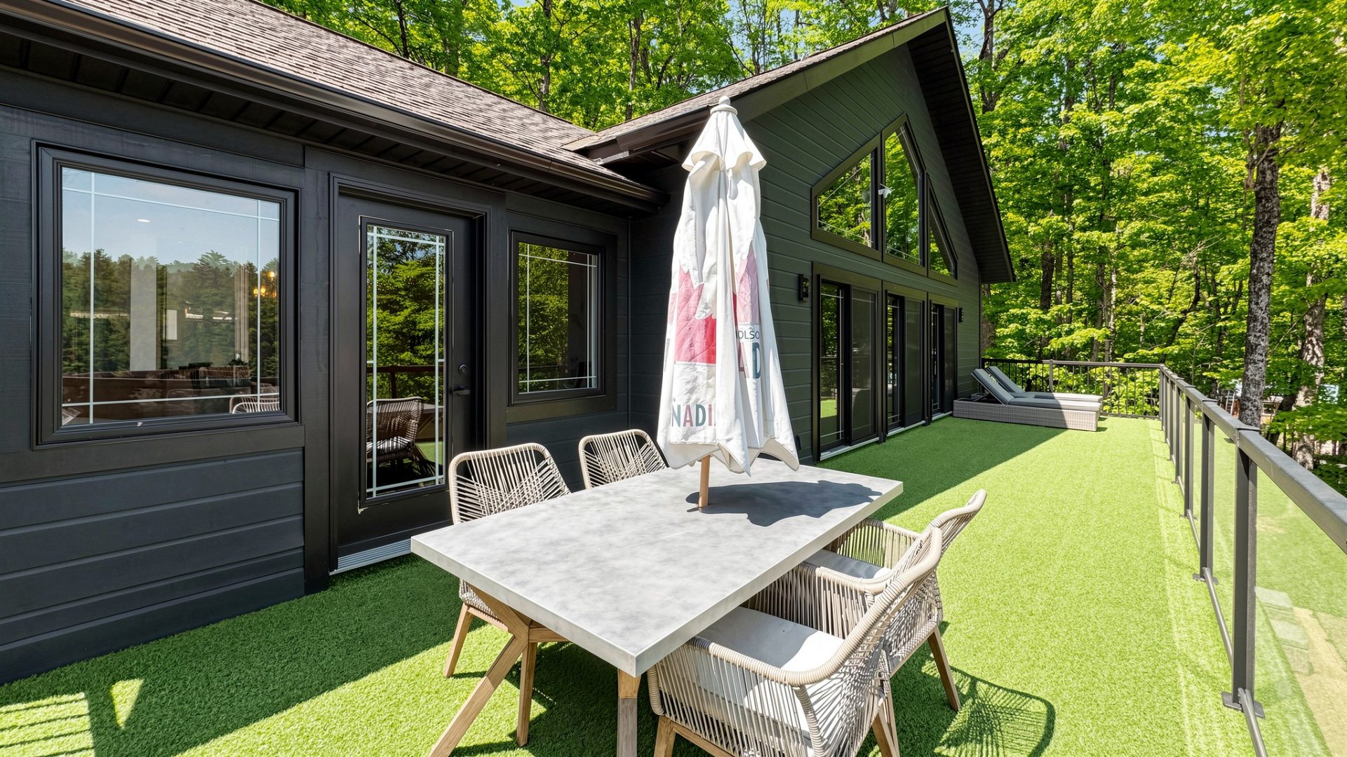 An outdoor dining set with a closed umbrella on light green turf
