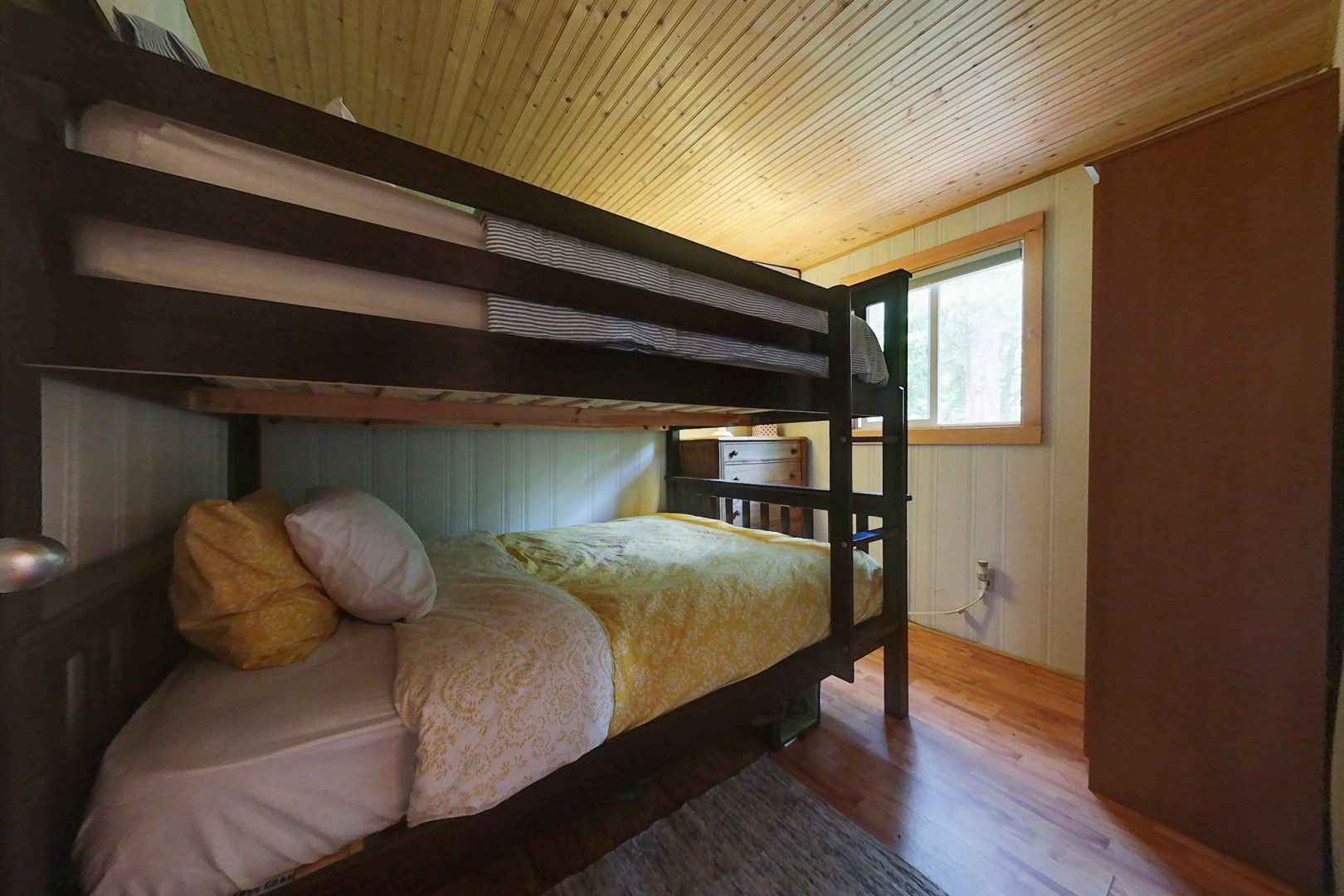 A dark wood bunk bed with yellow covers