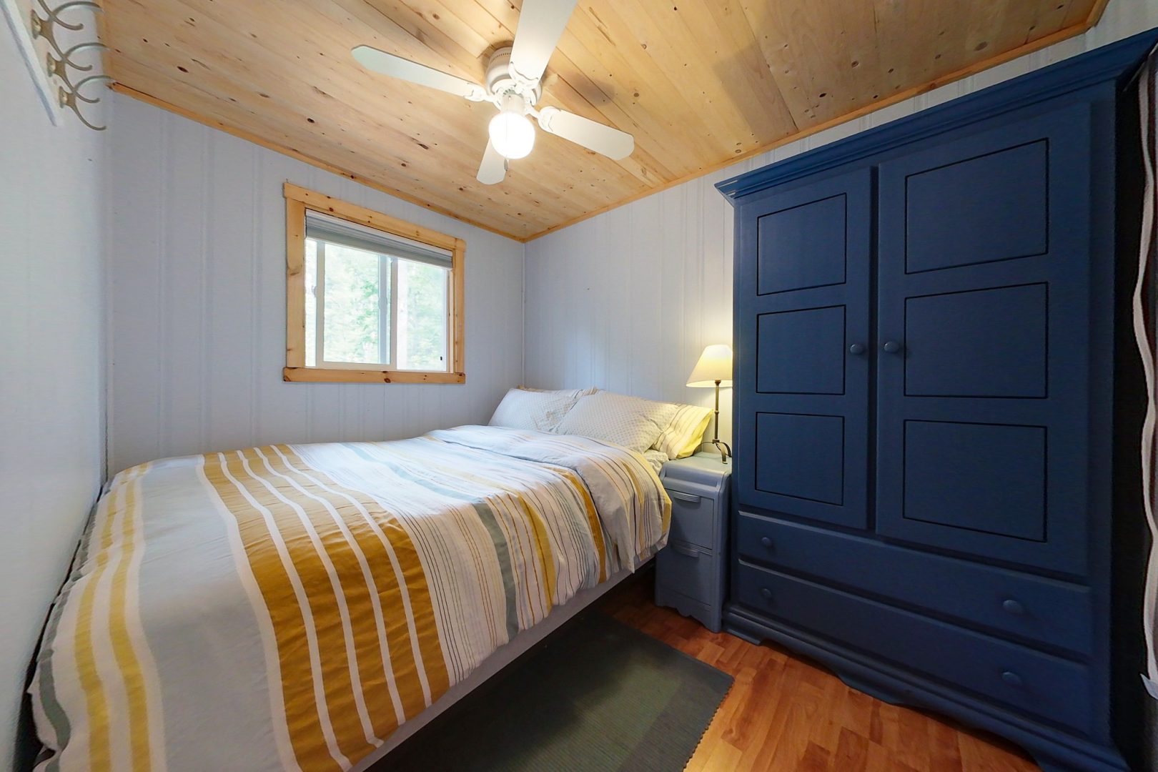 A small bed with a white and yellow striped cover in a white room