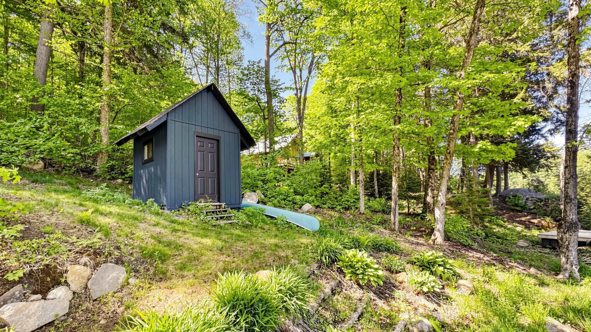 A dark navy wood shed on a rustic property.