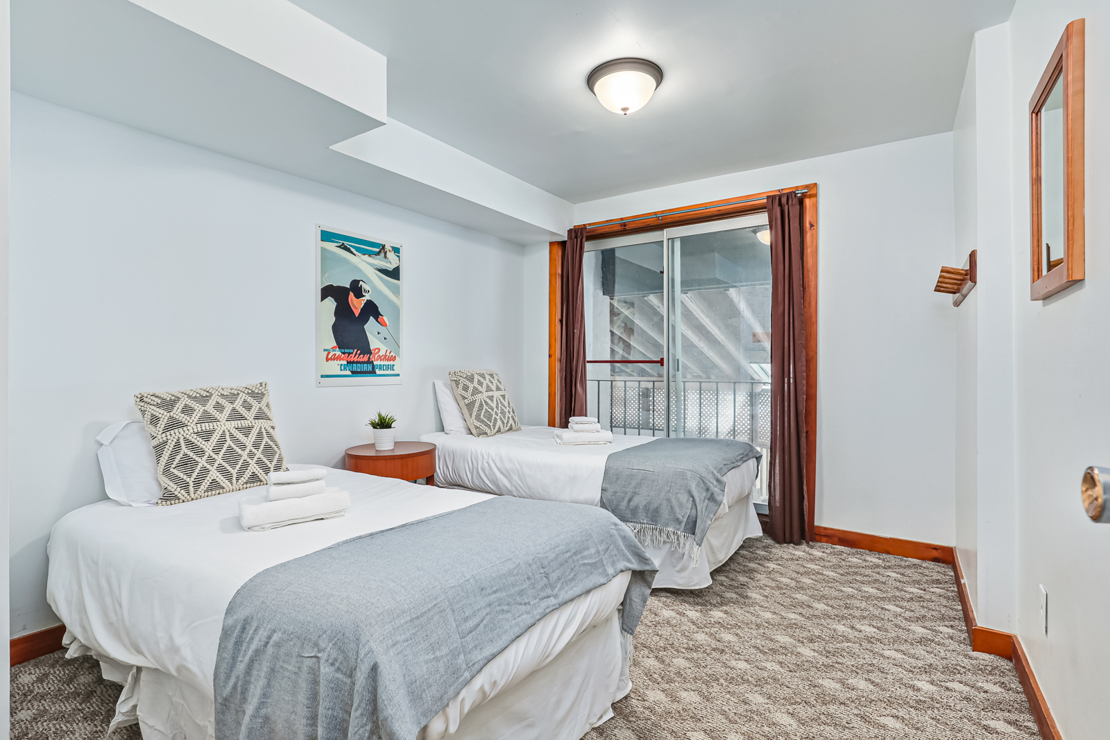 Two white beds with grey throw blankets in a white bedroom