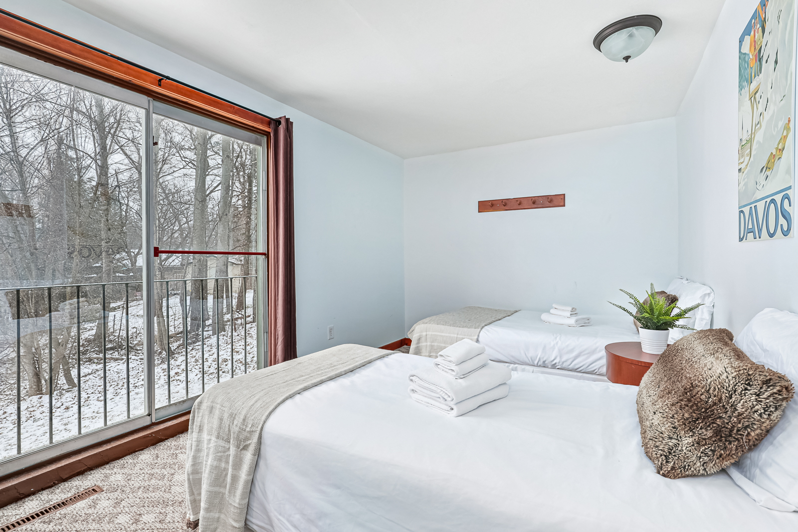 Two white beds in a white bedroom face a window