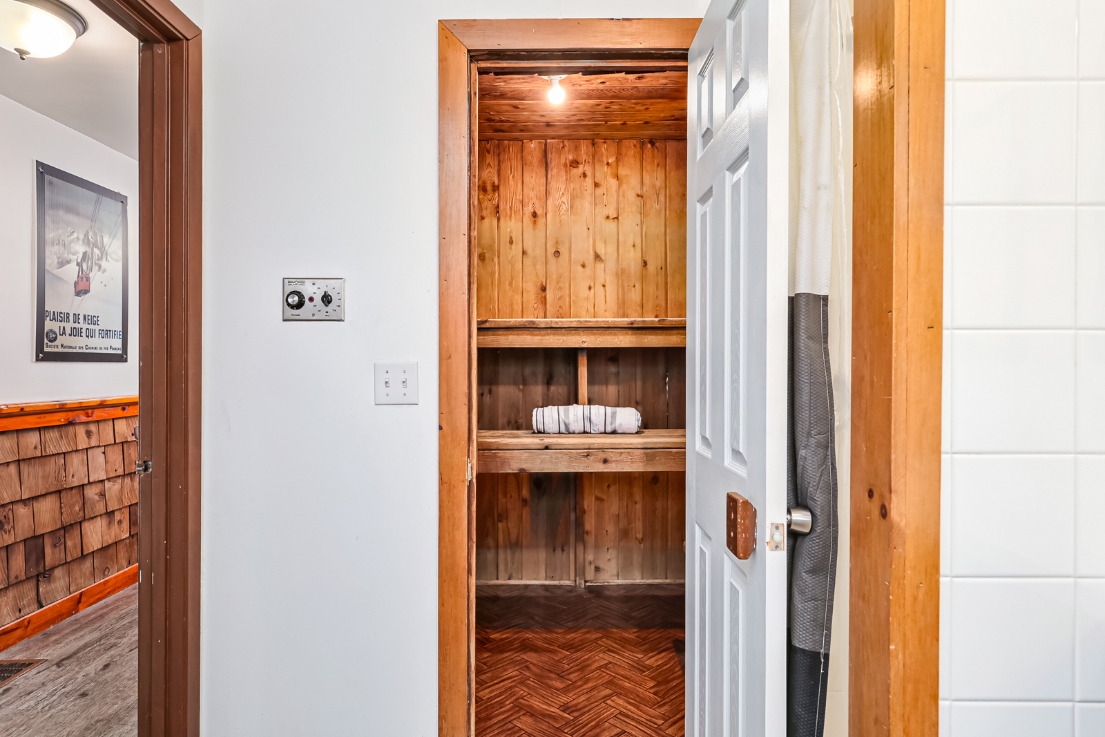 A sauna is tucked behind an open white door