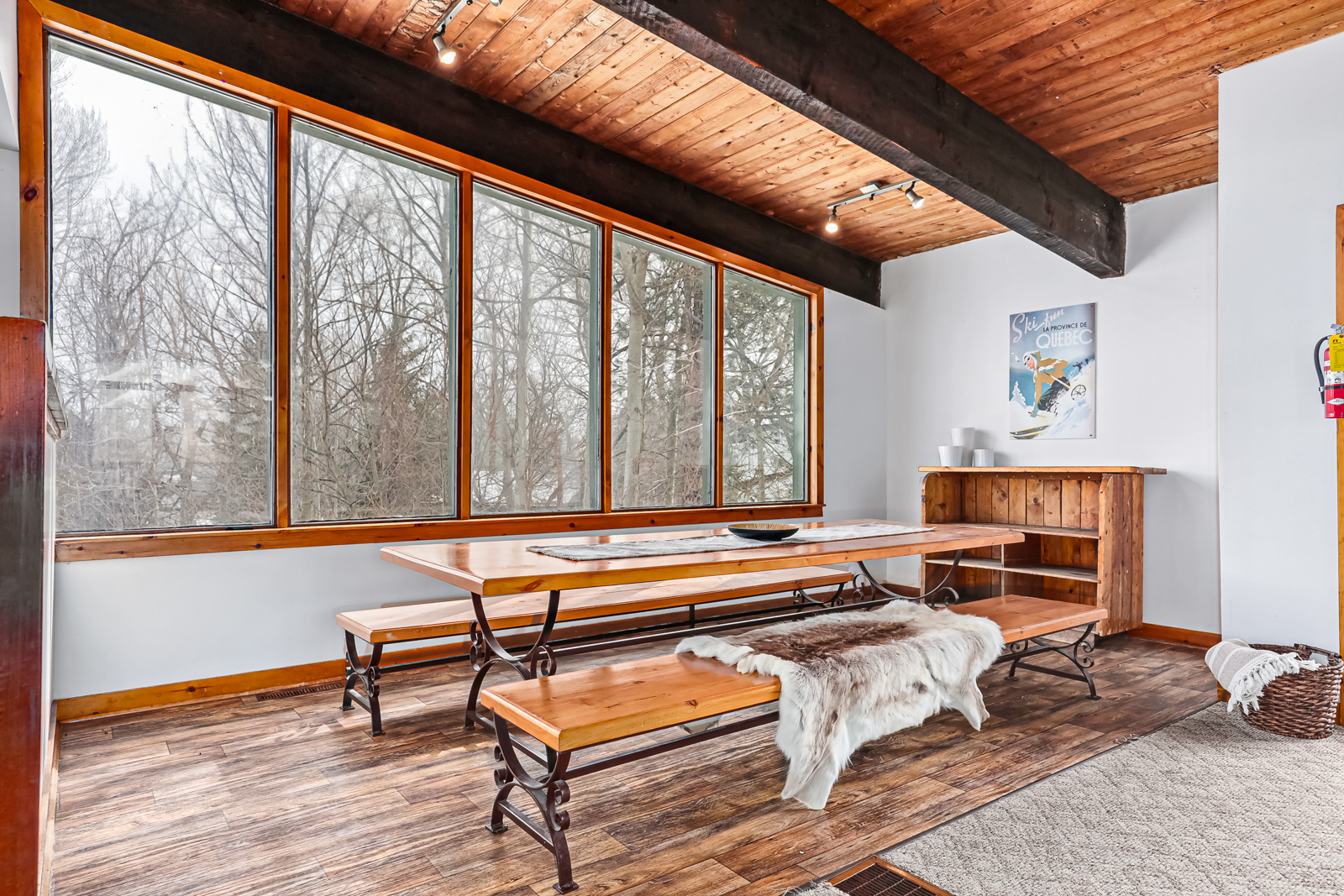 A long wood table with wood benches in front of a bright window