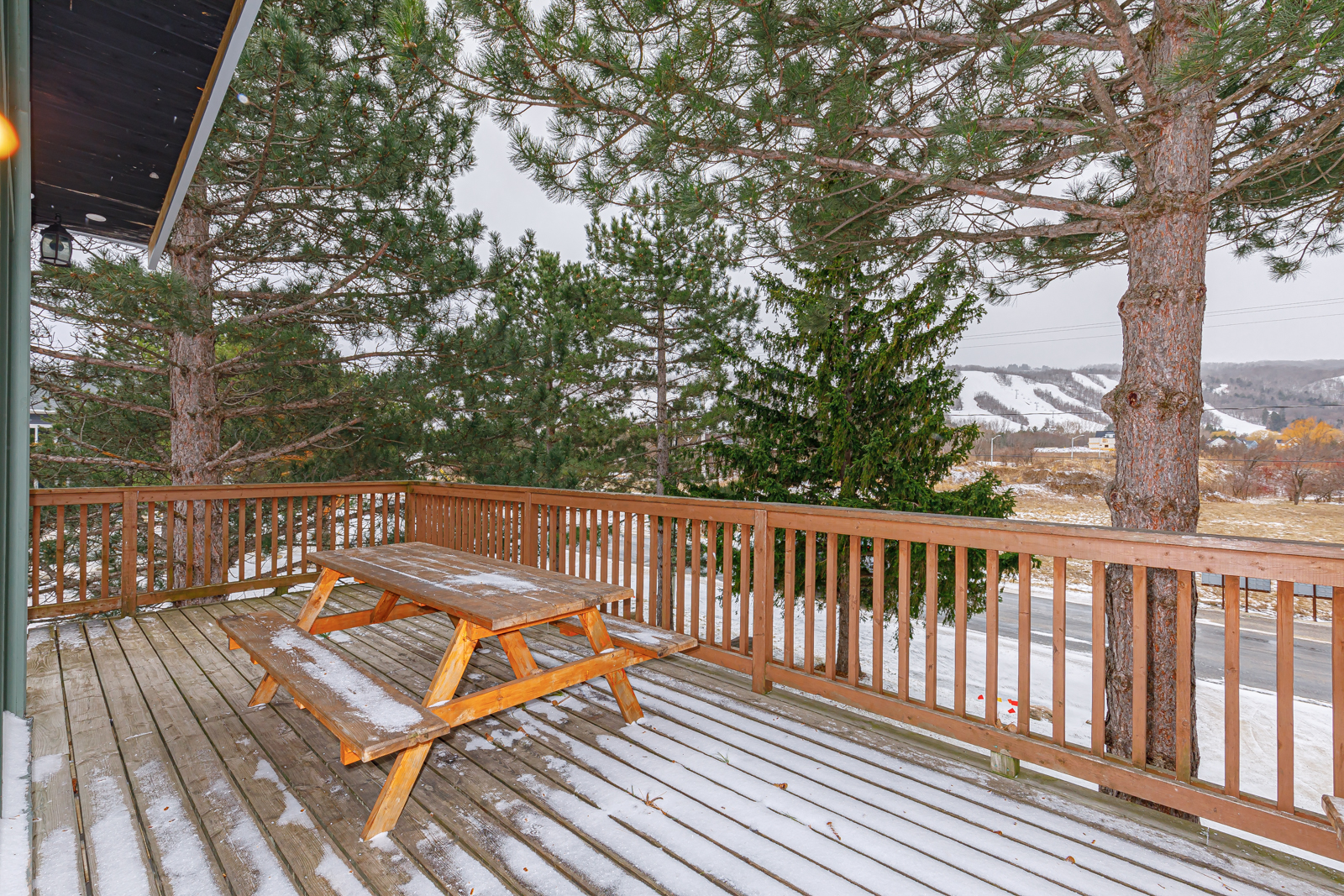 A picnic table with a dusting of snow on a wood deck