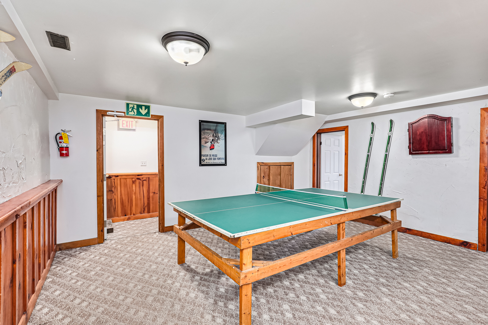 A green ping pong table in a white room with beige carpeting