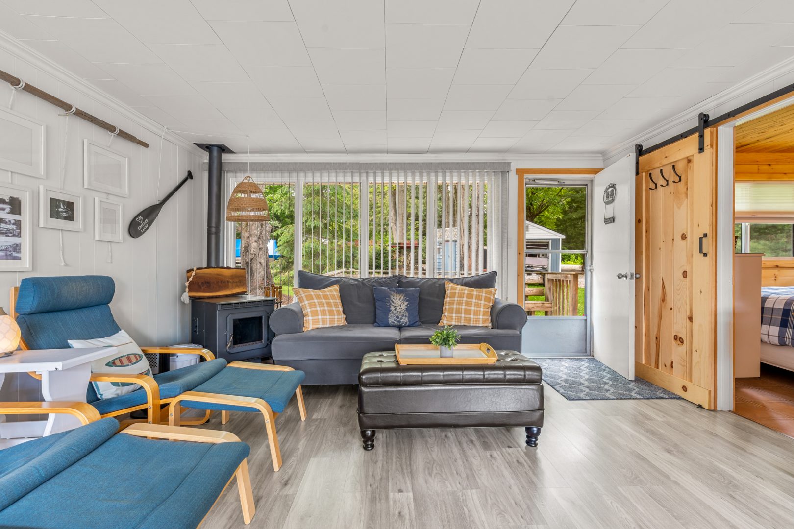 A grey couch next to a woodstove in a white living room