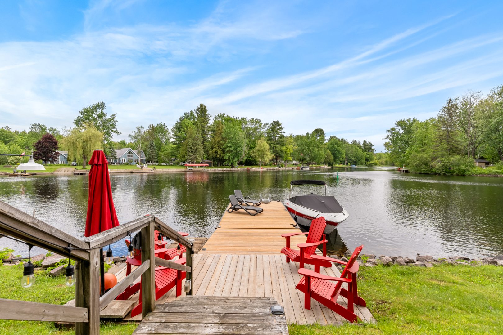 A dock with red Muskoka chairs along the shoreline