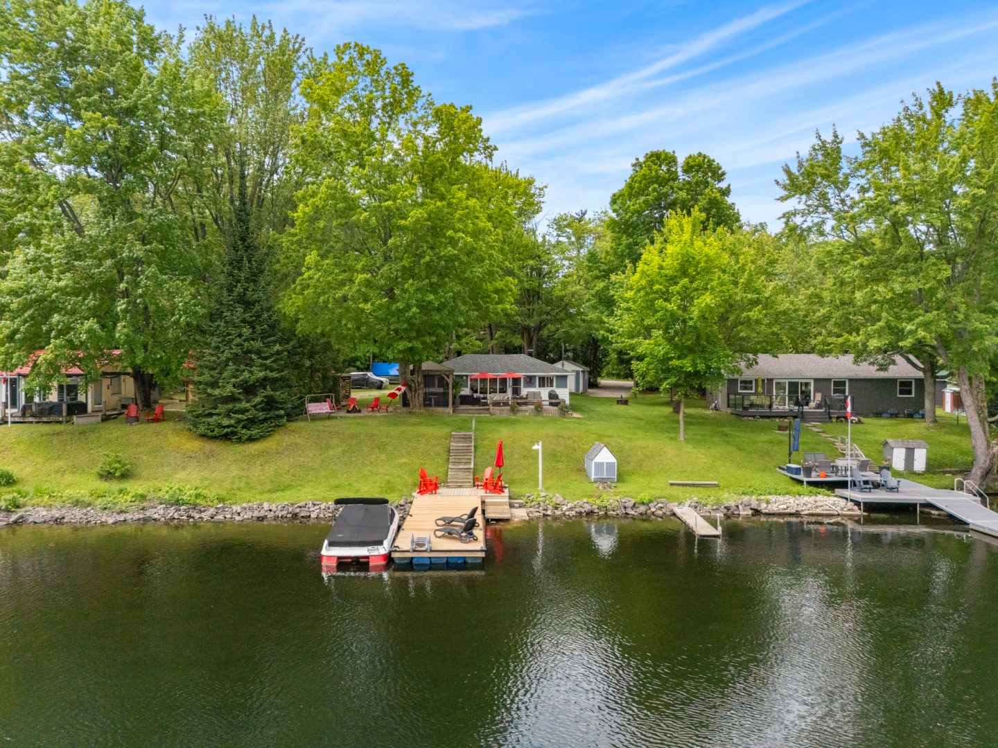 A cottage tucked away on a grassy lawn on a waterfront property