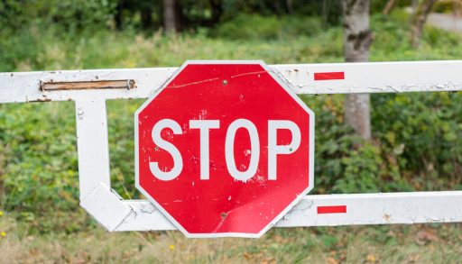 Red stop sign on a gate over a closed driveway
